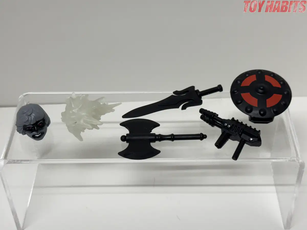 The accessory assortment includes a black sword, axe, and shield with red accents, a custom blaster, and a creamy white glow-in-the-dark blast effect.