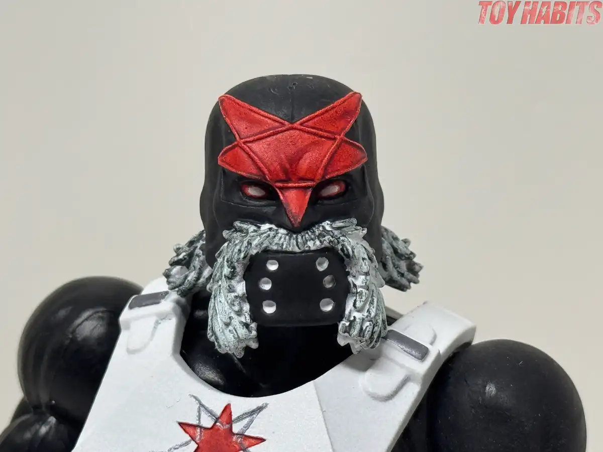 The masked head features an angular red forehead emblem, narrow red eyes, sculpted silver-gray facial hair, and a black mouth covering with six silver studs.